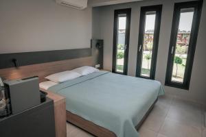 a bedroom with a large bed with windows at Elizabeth Queen Luxury Rooms in Paralia Katerinis