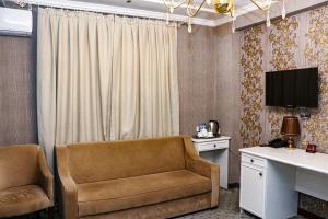 a room with a couch and a desk and a television at ORZU HOTEL in Namangan