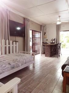 a bedroom with a bed and a living room at Peace Cottages Uvongo. in Uvongo Beach