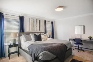 a white bedroom with a large bed and a desk at Stunning 4BR at ChampionsGate - Pool & BBQ in Kissimmee