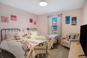 a bedroom with two beds and a chair and a window at Stunning 4BR at ChampionsGate - Pool & BBQ in Kissimmee