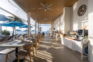 a restaurant with tables and chairs with a view of the ocean at Three Trees Samui Resort - Sarocha Villa in Lamai
