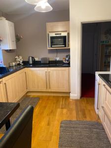 a kitchen with wooden cabinets and a microwave at Gramhor House in Dumfries +5 photos