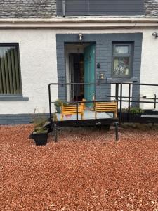 a house with two benches in front of a door at Gramhor House in Dumfries