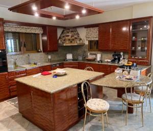 a kitchen with wooden cabinets and a island with chairs at Stone Horizon Villa in Eretria +9 photos