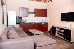 a living room with a couch and a kitchen at Falcon Lodge (ET) in Bela-Bela