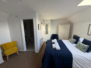 a bedroom with a large bed and a yellow chair at House Martin in Ipplepen +35 photos