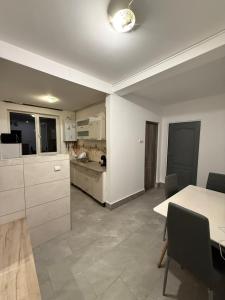 a kitchen with white cabinets and a table with chairs at Turda central apartament in Turda