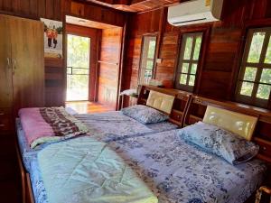 two beds in a room with wooden walls and windows at Meesaeng Homestay in Thalang
