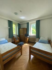 a bedroom with two beds and a chair and window at Gästehaus am Main in Randersacker