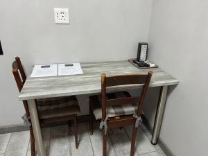 a wooden table with two chairs and a desk with a book at Lafenis Selfsorg in Jan Kempdorp