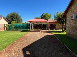a patio with a red umbrella in a yard at Lafenis Selfsorg in Jan Kempdorp +5 photos