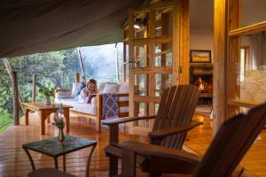 a woman sitting on a couch in a living room with a fireplace at Olesamara Collection in Nanyuki