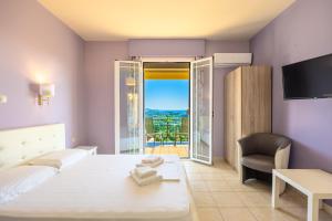 a bedroom with a bed and a chair and a balcony at Ionian Balcony Hotel Apartments in Khavdháta