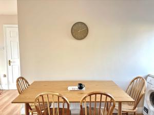 a dining room table with chairs and a clock on the wall at Cobh Coastline Hideaway in Cobh +8 photos