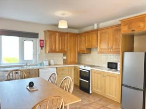 a kitchen with wooden cabinets and a table with chairs at Cobh Coastline Hideaway in Cobh