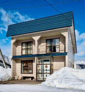 a small house with a garage in the snow at Migiwa House in Rankoshi