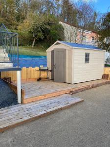 a small white shed sitting on a wooden deck at Maison Les Cygnes face au lac in Changey