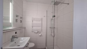 a white bathroom with a shower and a sink at Terrassenhaus, FeWo 32 in Duhnen