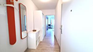 a hallway with white walls and a red mirror at Terrassenhaus, FeWo 32 in Duhnen