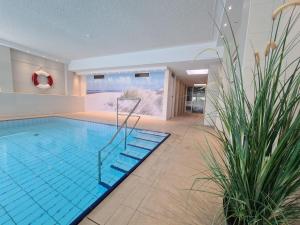 a large swimming pool in a building with at Terrassenhaus, FeWo 32 in Duhnen +10 photos