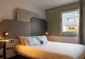 a bedroom with a large white bed with a window at B&B HOTEL Lourdes Centre Gare 3 étoiles in Lourdes