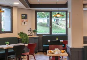 a restaurant with tables and chairs and a window at B&B HOTEL Lourdes Centre Gare 3 étoiles in Lourdes