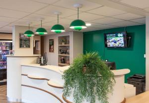 a bar in a pharmacy with a green wall at B&B HOTEL Lourdes Centre Gare 3 étoiles in Lourdes