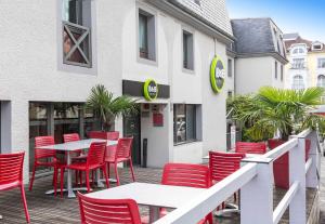 a restaurant with red chairs and tables in front of a building at B&B HOTEL Lourdes Centre Gare 3 étoiles in Lourdes