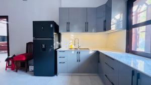 a kitchen with white cabinets and a black refrigerator at Spacious Siem Reap Sanctuary in Phumi Ta Phul