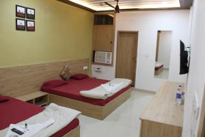 a small room with two beds and a television at Rajadhiraj Ashray- Nr Mathura Railway Station in Mathura