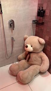 a large teddy bear sitting on the floor in a shower at Teddy in Malpe +8 photos