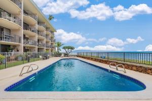 a swimming pool in front of a building at Kahana Reef 221 · KR 221 BeachFront Condo w Ocean Views Pool BBQ in Kahana