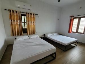 two beds in a room with two windows at Akalapuzha Homestay in Kozhikode