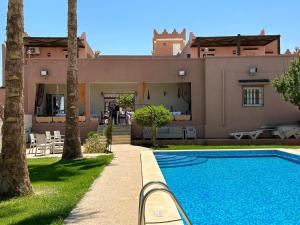a villa with a swimming pool in front of a house at Dar Elferdaous in Al Medou