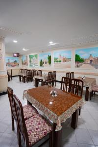 a dining room with tables and chairs and paintings at RAY Boutique Hotel withTerrace in Bukhara