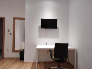 a desk with a chair and a television on a wall at Hostel i Restoran SEQUOIA in Slatina