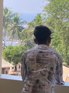 a man looking out of a window at the ocean at Siva Bharg Residency in Kovalam