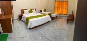 a bedroom with two beds and a desk and a window at Siva Bharg Residency in Kovalam +2 photos