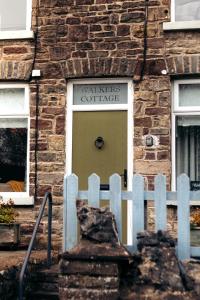 a brick building with a white fence in front of a door at 4 Walkers Cottage - Cosy, dog friendly with private unique BBQ hut! in Pont Sticill