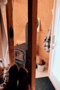 a person sitting in front of a stove in a tiny house at Prêt-à-camper, dôme in La Tuque