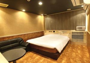 a small bedroom with a bed and a chair at ホテル彩柏市若柴店 in Kashiwa
