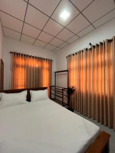 a bedroom with a large white bed and curtains at Green Sapphire Home Stay in Anuradhapura