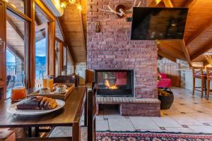 a living room with a fireplace and a table with a plate of food at Rigas Hotel Arachova in Arachova
