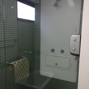 a green tiled bathroom with a sink and a window at Apartamento Boa Viagem in Recife