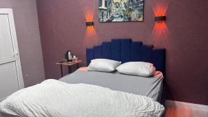 a bedroom with a bed with a blue headboard and two lights at Çankaya Otel in Altındağ