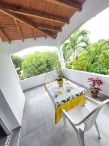 a patio with a table and chairs on a balcony at Chez Liliane in Bouillante