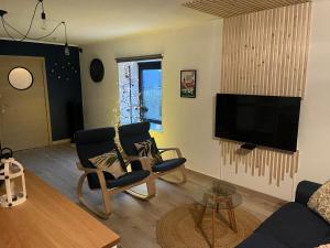 a living room with two chairs and a flat screen tv at Le repaire du raton laveur in Rance