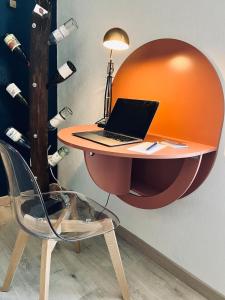 a desk with a laptop on it with a chair at Le repaire du raton laveur in Rance