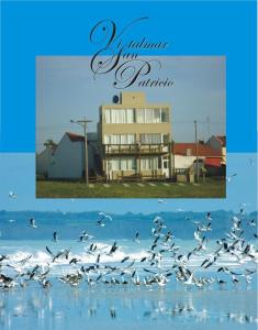 un rebaño de aves volando sobre el agua con un edificio en Departamentos Vistalmar San Patricio en Mar del Plata